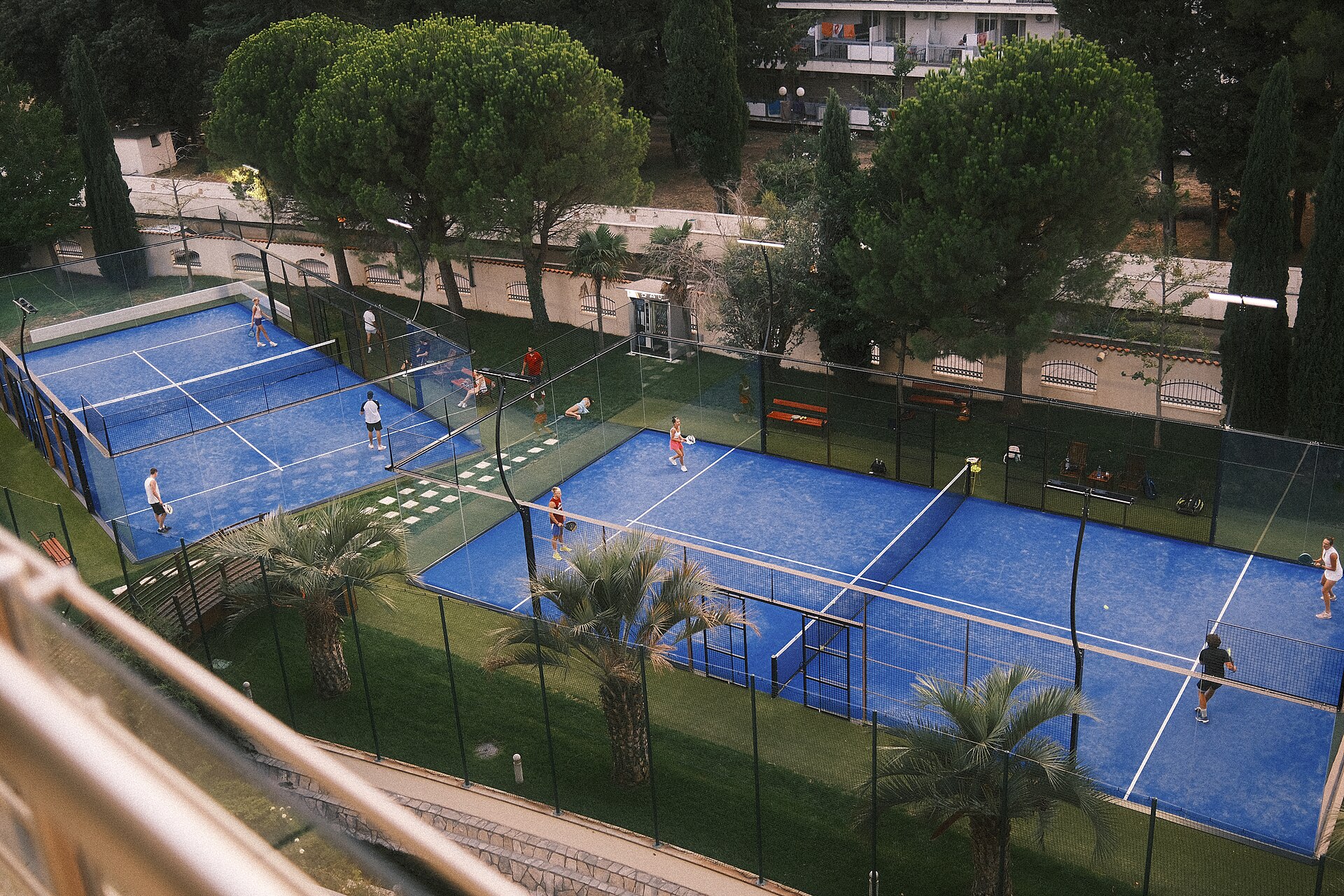 Blue padel courts seen from above, matches underway